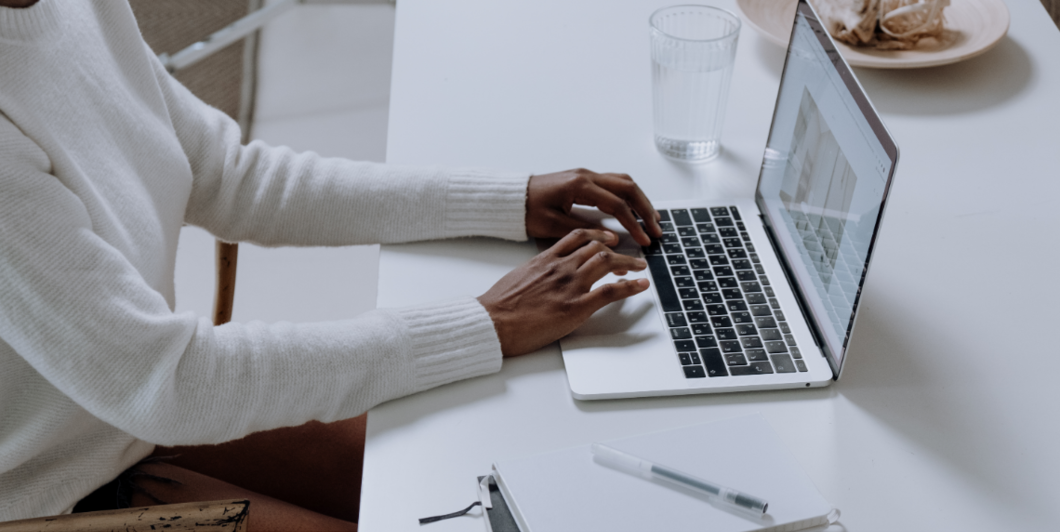 person in white jumper using a laptop