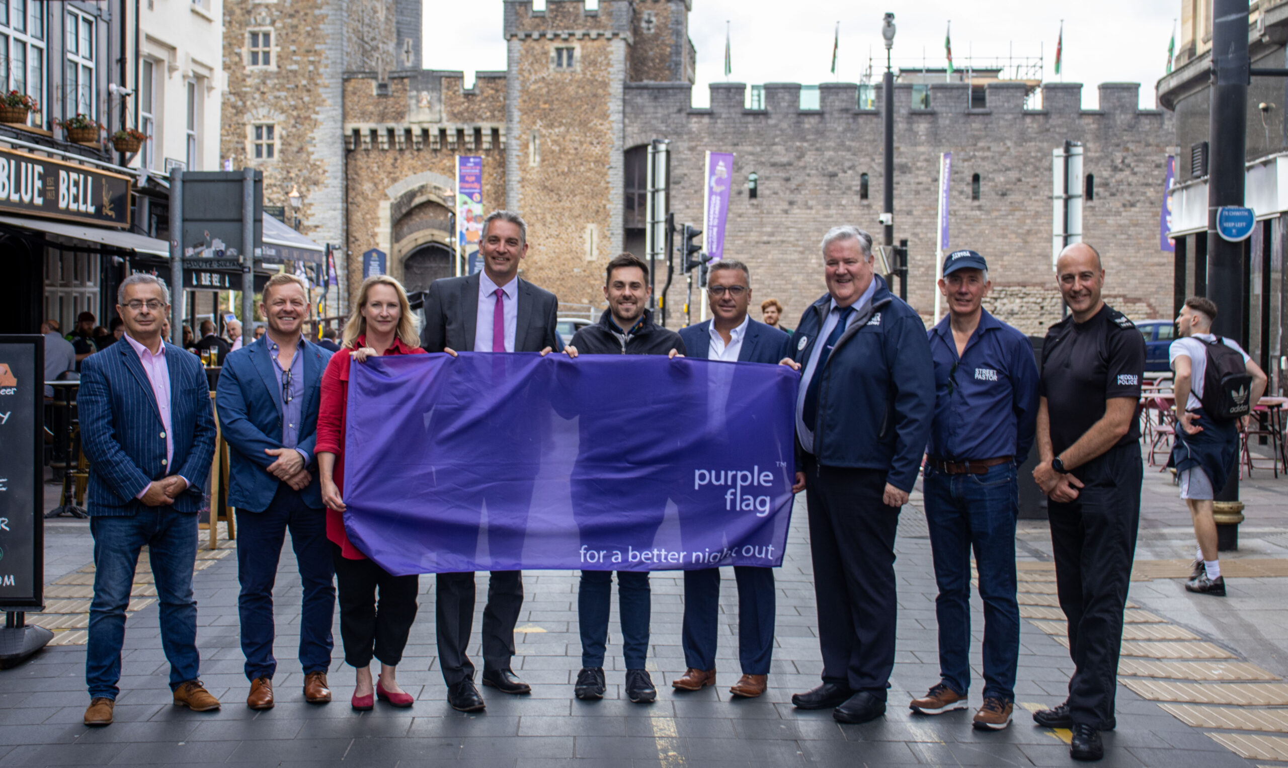 group of people standing on Cardiff high street with purple flag