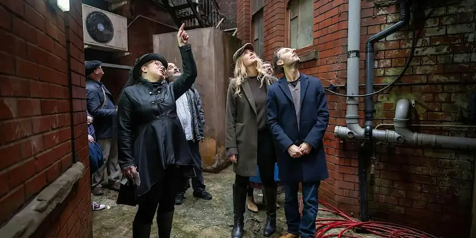 Group of 6 people pointing and looking up spotting something interesting on a tour of the arcades